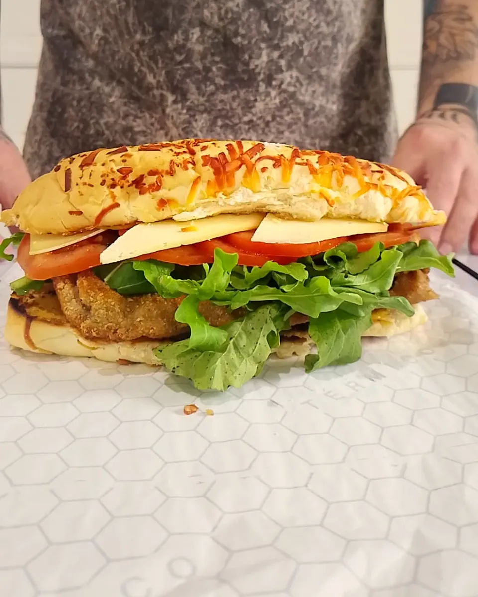 Milandwich de carne recién hecho, con rúcula, tomate y queso sardo